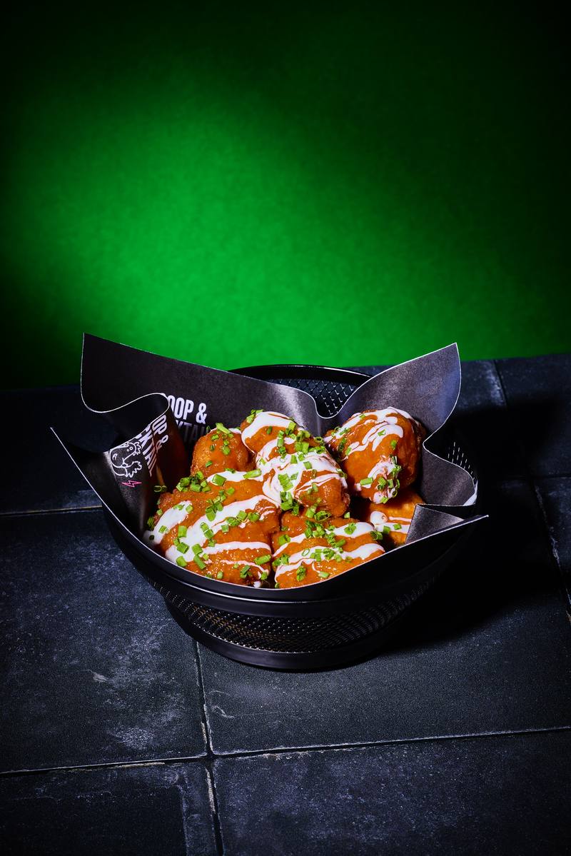 Buffalo wings with ranch drizzle and chives in a black basket